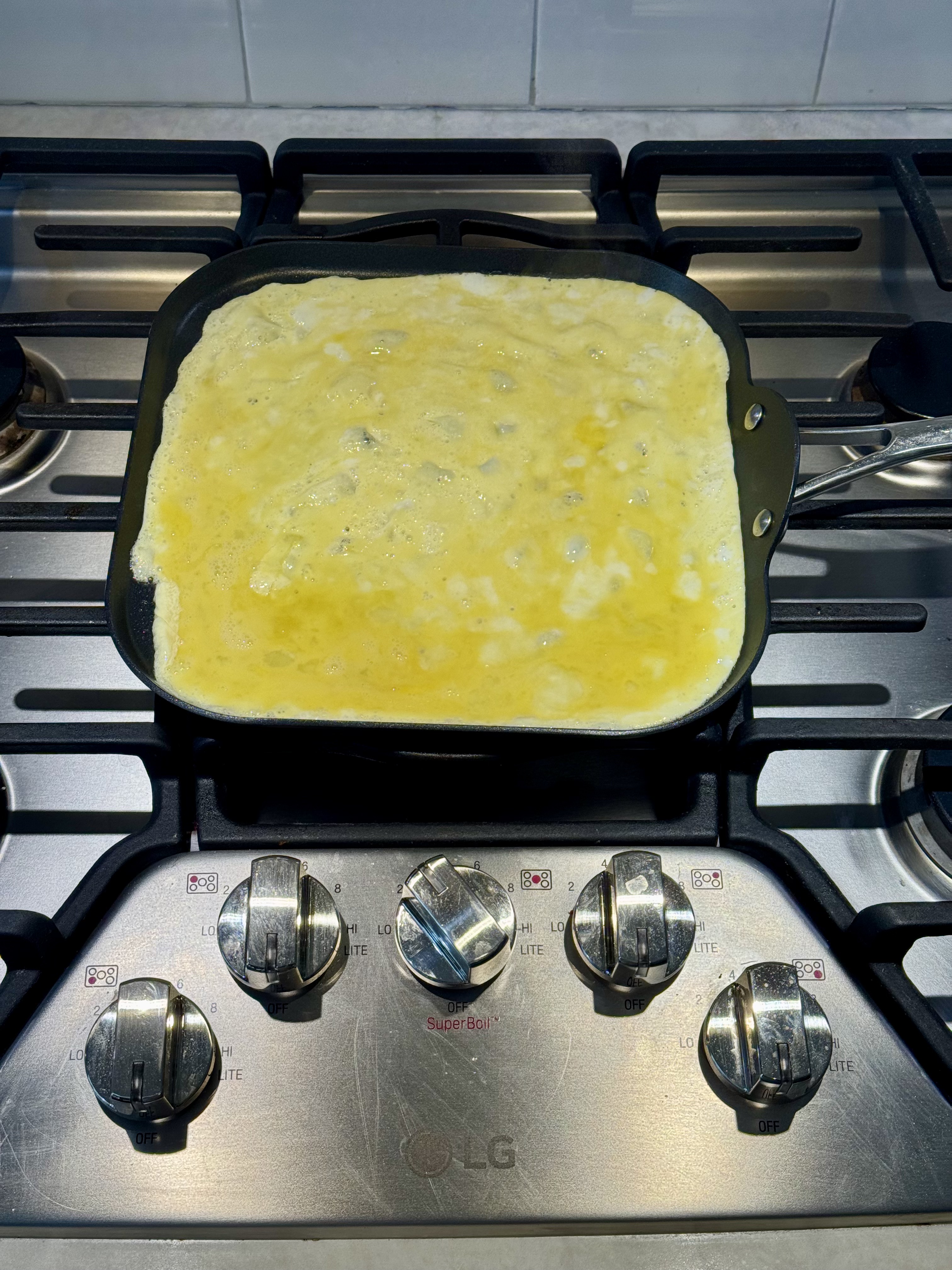 Eggs cooking flat on griddle before folding